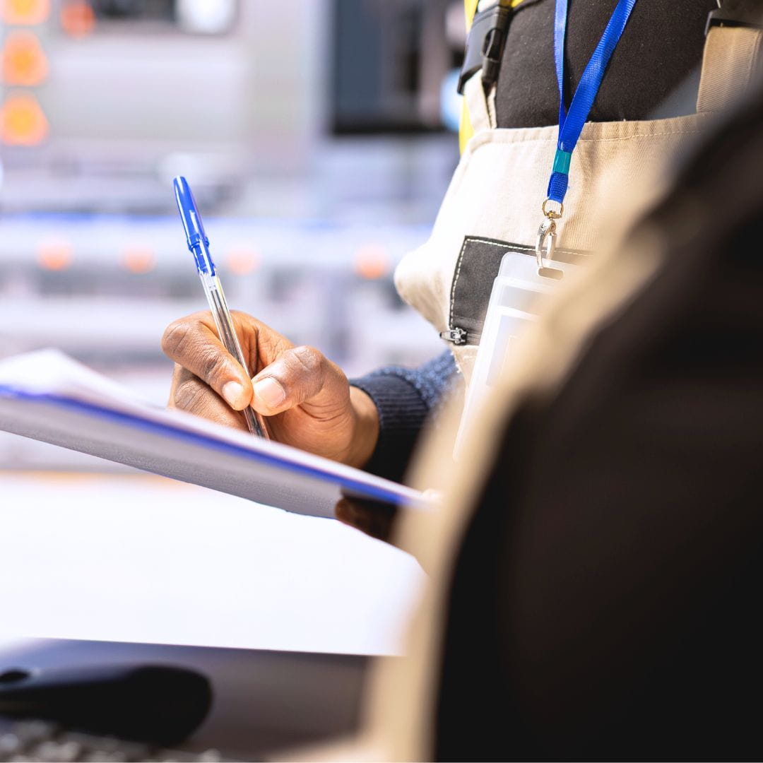 Aviation inspector filling out a checklist on a notepad during an aircraft safety inspection on the tarmac.